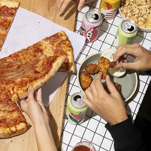 Person holding sliced pizza on white ceramic plate