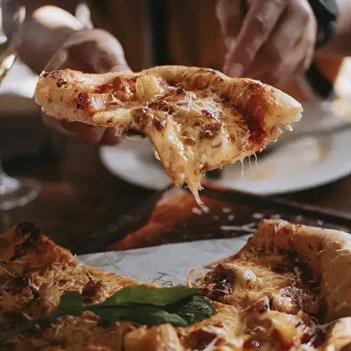 A slice of pizza is being lifted with the rest of the pizza that will be served.